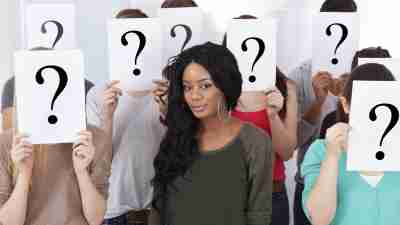 Student Surrounded By Classmates Holding Question Mark Signs