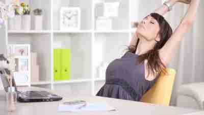 A woman with ADHD taking a break to stretch in her office.