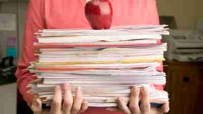 A stack of papers with an apple on top, representing parents and teachers working together