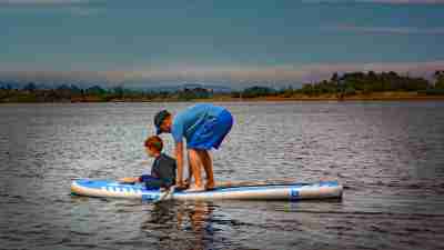 A feather and his neurodivergent son on a paddle board