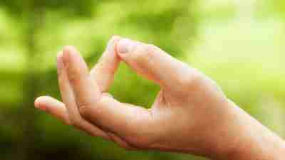 A man practices mindfulness techniques by placing his hands in lotus position.