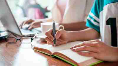 A child's hands writing in a notebook while learning how to study effectively with ADHD