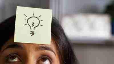 A woman with ADHD has a post-it with a lightbulb stuck to her forehead.