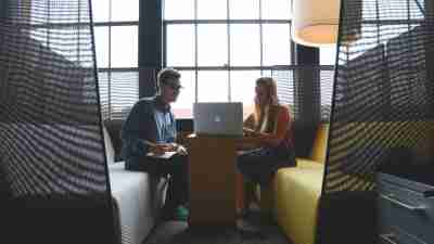 Two adults with ADHD successfully working together on laptop in office