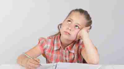 Young girl looks bored, distracted as she sits with her binder doing homework.