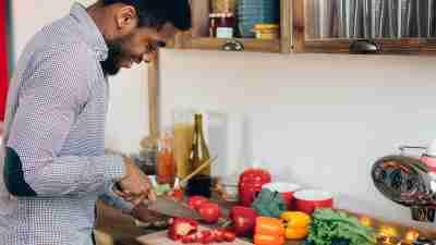 Man cutting a bell pepper in his kitchen.