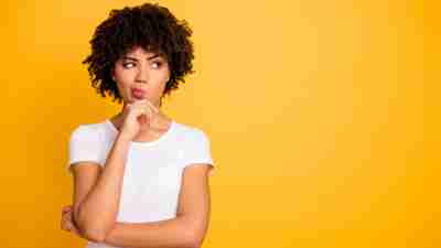 Close up photo beautiful amazed she her dark skin lady arms hands chin think over not sure homework diligent student look empty space wearing casual white t-shirt isolated yellow bright background.