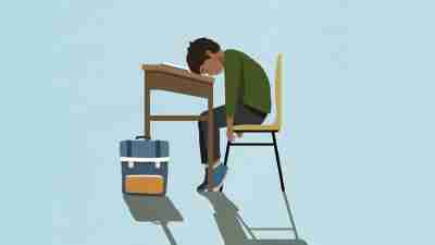 Exhausted schoolboy sleeping on classroom desk