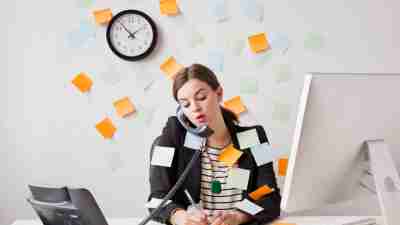 Studio shot of young woman working in office covered with adhesive notes. Jessica Peterson/Getty Images.