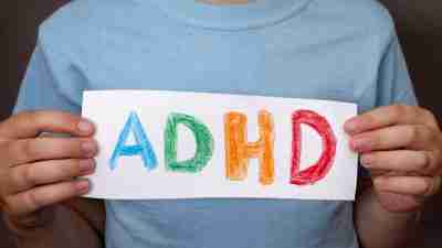 Young boy holding a hand-drawn "ADHD" sign.