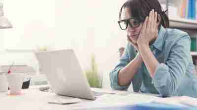 Bored ADHD woman in the office working with a laptop and staring at computer screen