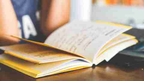 Teen girl with ADHD reading notebook at high school