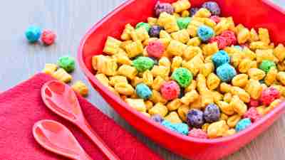 Bowl of sugary cereal with spoon near it on wooden table would make a poor breakfast for someone with ADHD