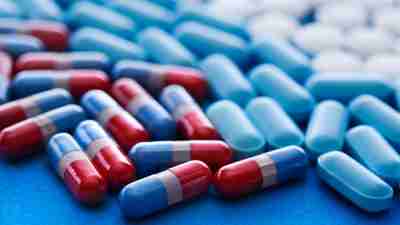 Different types of ADHD pills on blue surface