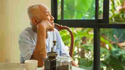 A senior man with ADHD, staring quietly out the window of his home