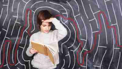 A young boy with autism standing calmly in front of a chalkboard, thanks to a behavior intervention plan